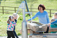 Playground pump with integrated pressure connection in the column, programmable flushing device