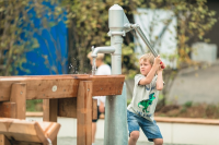 Playground pump with integrated pressure connection in the column, programmable flushing device