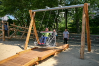 Rollstuhlfahrerschaukel mit Holzkonstruktion als Bodenmodellierung